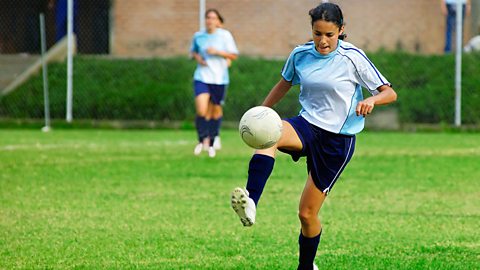 Female teenager kicking a football
