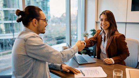 Man shaking hands with a woman behind a desk