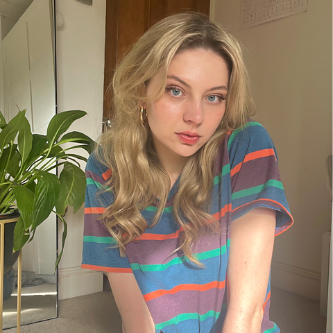 A blonde woman wearing a stripy top sits on the floor