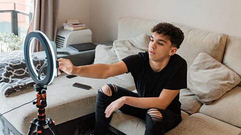 A teenager sets up his ring light with his phone ready to record a video