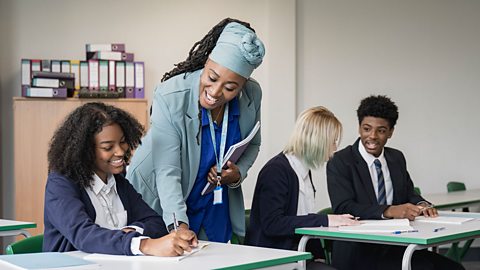 Teacher helping a student with two other students chatting in the background