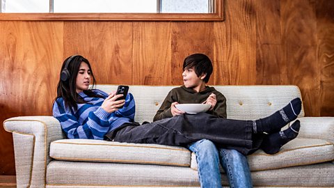 Older sister and younger brother hanging out together on the sofa