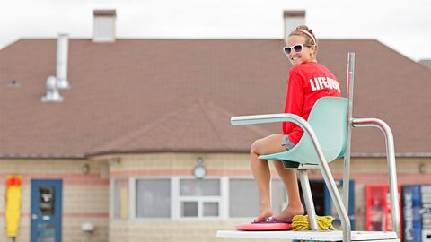 Young female lifeguard working at an outside swimming pool