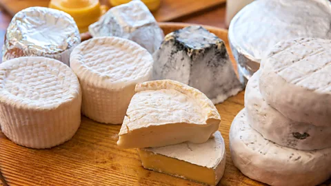 Alamy Rounds and wedges of different cheeses on a wooden board (Credit: Alamy)