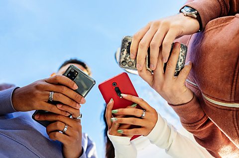 Teenagers look at mobile phones