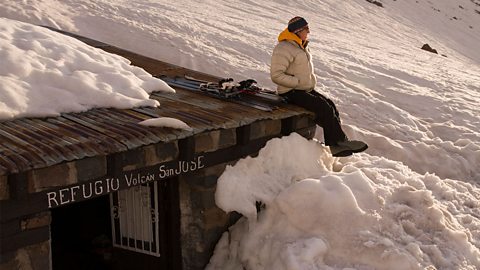 Woman sitting on the roof of a show covered hut, on the side of a mountain