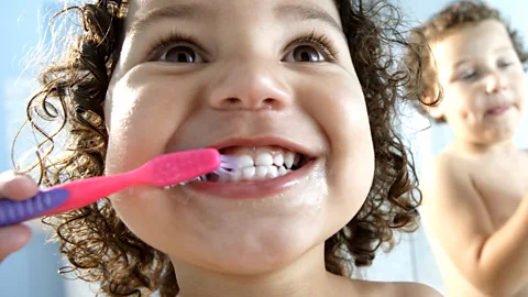 Getty Images Children brush their teeth using a plastic hand brush (Credit: Getty Images)