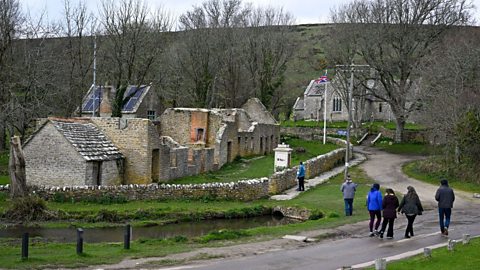 A group of people walk past the deserted village of Tyneham