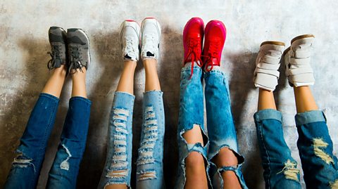 Four pair of legs covered in distressed jeans. The people pictures are all wearing trainers.