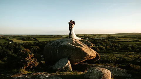 Enchanted Brides Anna and Dylan Rood, a married geologist couple, pose for their wedding photos on a boulder in Cornwall (Credit: Enchanted Brides)