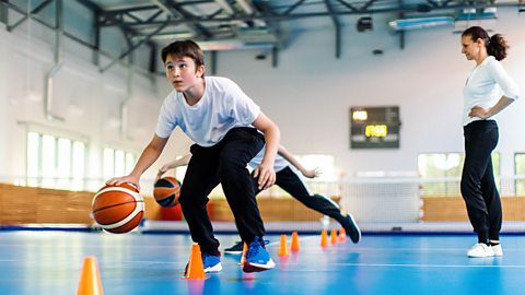 Teenage boy practising basketball dribbling