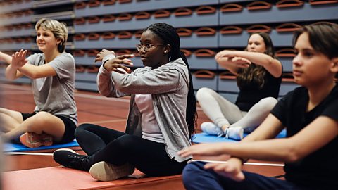 A group of teenagers sat down and performing yoga
