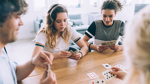 Male and female teenager playing cards with their parents