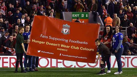 Liverpool and Everton fans hold a Fans Supporting Foodbanks banner on match day 