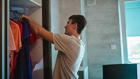 Male teenager arranging clothes in his wardrobe
