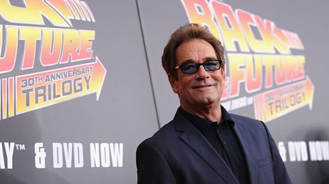 Musician Huey Lewis stood in front of a Back to the future billboard