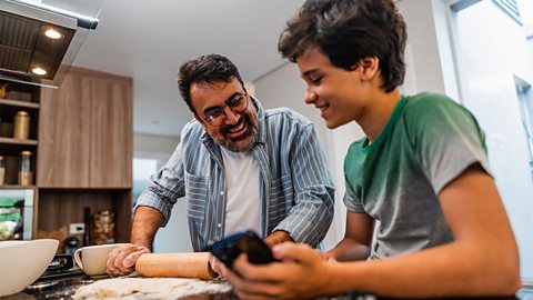 Father and teenage son following a baking recipe