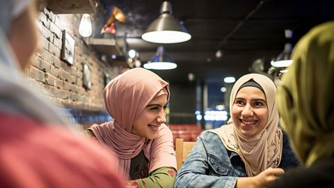 Four female teenage friends smiling and chatting in a restaurant