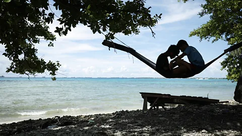 Getty Images Two children sit in a hammock on beach in Tuvalu (Credit: Getty Images)