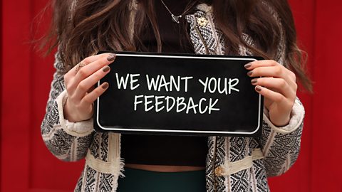 lady holding a sign saying we want your feedback.