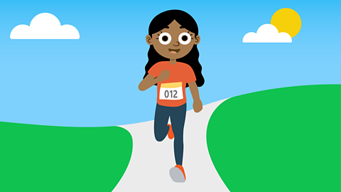 Maya running. She has long wavy black hair and is wearing an orange T-shirt with the number 012 on it, running trousers and shoes.