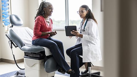 A doctor showing a patient some health results on a tablet.