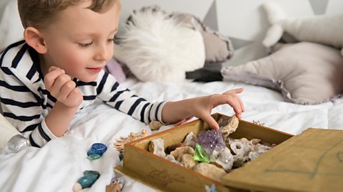 A young boy looks through the objects in his memory box - shells, rocks and crystals.
