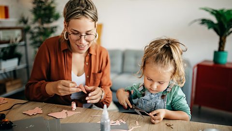 A mother and daughter carefully cut out leaf shapes for their crafty family tree design.