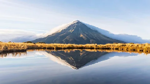 Alamy Mount Taranaki volcano in New Zealand reflected in a still lake (Credit: Alamy)