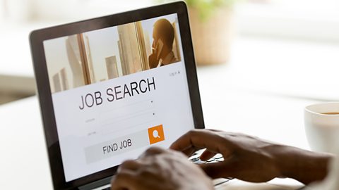 Person searching for a job on a external job search website. The site on the laptop says 'Job Search' and 'Find Job'