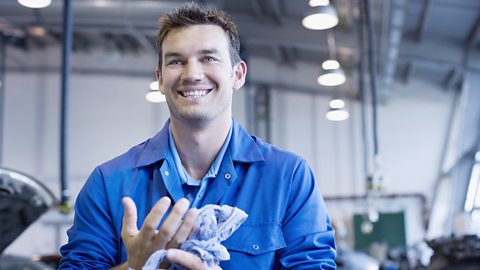 A male mechanic smiling as he cleans his hands as he is happy at work