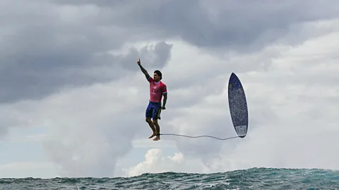 Getty Images Brazilian surfer poses mid-air with hand raised during Olympics men's surfing heats in Tahiti (Credit: Getty Images)