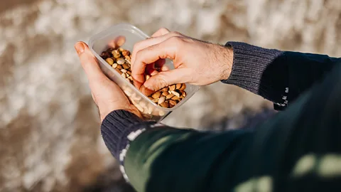 Getty Images A man picking mixed nuts out of a plastic box (Credit: Getty Images)