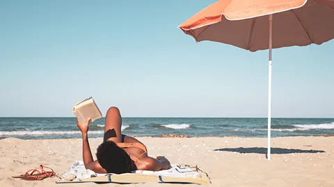 Getty Images A woman lying on the beach reading a book (Credit: Getty Images)