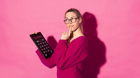 Lady in pink jumper doing a calculation on an oversized calculator.