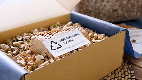 A box full of recyclable material used as packaging pellets. There is a card on top that says 100% recyclable reusable.