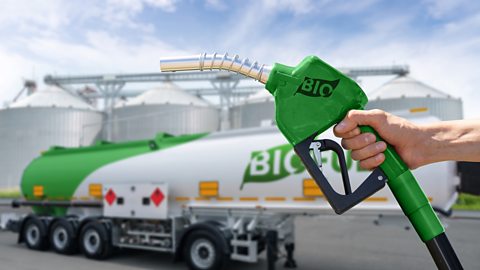 A green fuel pump nozzle in front of a bio fuel lorry