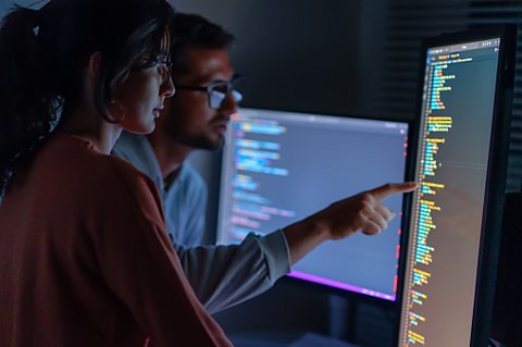 Computer and two people looking at it, training for coding, cyber security or software