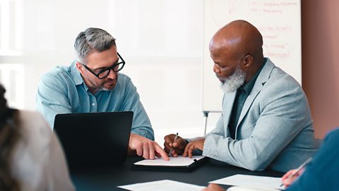 Two business owners looking over a printed version of another business accounts