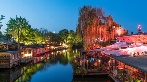 Alamy Colourfully lit buildings along a river in Berlin (Credit: Alamy)