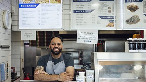 chip shop working standing at the till of a chippy