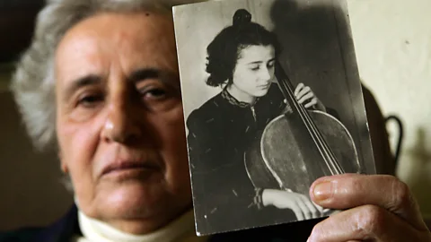 Getty Images Anita Lasker-Wallfisch holding a photograph of herself when she was younger playing the cello (Credit: Getty Images)