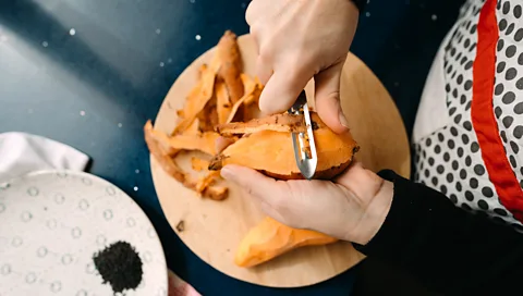 Getty Images A person peels a sweet potato using a peeler (Credit: Getty Images)