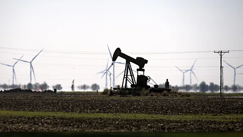 Getty Images A flat landscape with drilling apparatus, a power line and wind turbines (Credit: Getty Images)