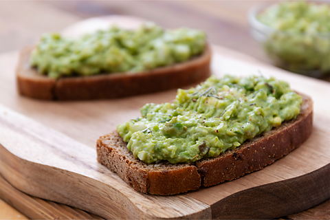 Two slices of avocado on toast placed on top of a chopping board