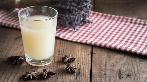 Alamy A glass of pastis on a table surrounded by star anise and a cloth with a bushel of lavender in the background (Credit: Alamy)