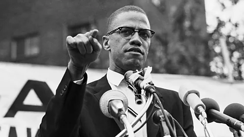 Getty Images A black-and-white photo of Malcolm X speaking at a podium (Credit: Getty Images)