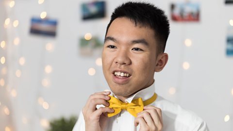 Teenage in his bedroom adjusting his tie.