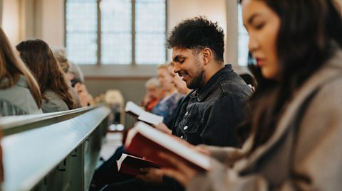 Young man reading a hymn book while sitting in church