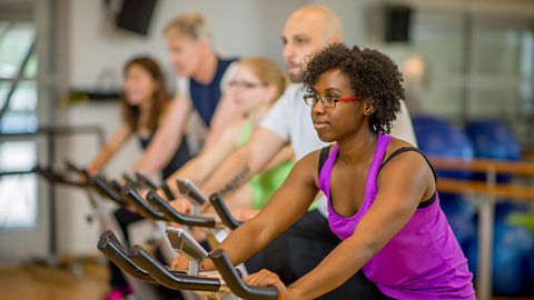 People taking part in a cycling class at the gym.